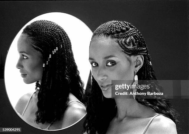 Portrait of American fashion model and actress Beverly Johnson, with braided hair, as she poses beside a mirror, New York, 1970s.