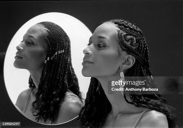 Portrait of American fashion model and actress Beverly Johnson, with braided hair, as she poses beside a mirror, New York, 1970s.
