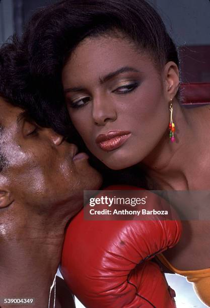 Close-up portrait of model Wanakee Pugh as she holds a boxing glove to the chin on an unidentified male model, New York, 1980s.