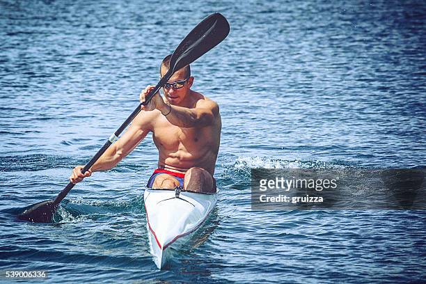 young muscular man during kayak sprint training on still water. - single scull stockfoto's en -beelden