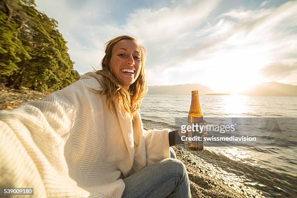 cheerful young woman enjoys a drink by the lake shore - bottle beer bildbanksfoton och bilder