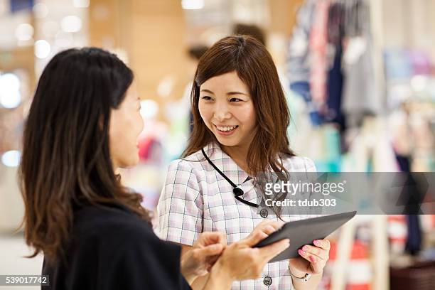 vendedor de loja usando uma tabuleta digital para ajudar o cliente - customer focused - fotografias e filmes do acervo