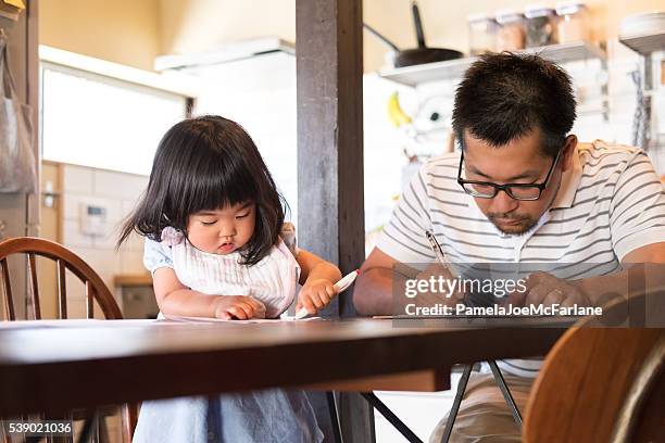 japanese father and daughter filling out paperwork on kitchen table - writing copy stock pictures, royalty-free photos & images