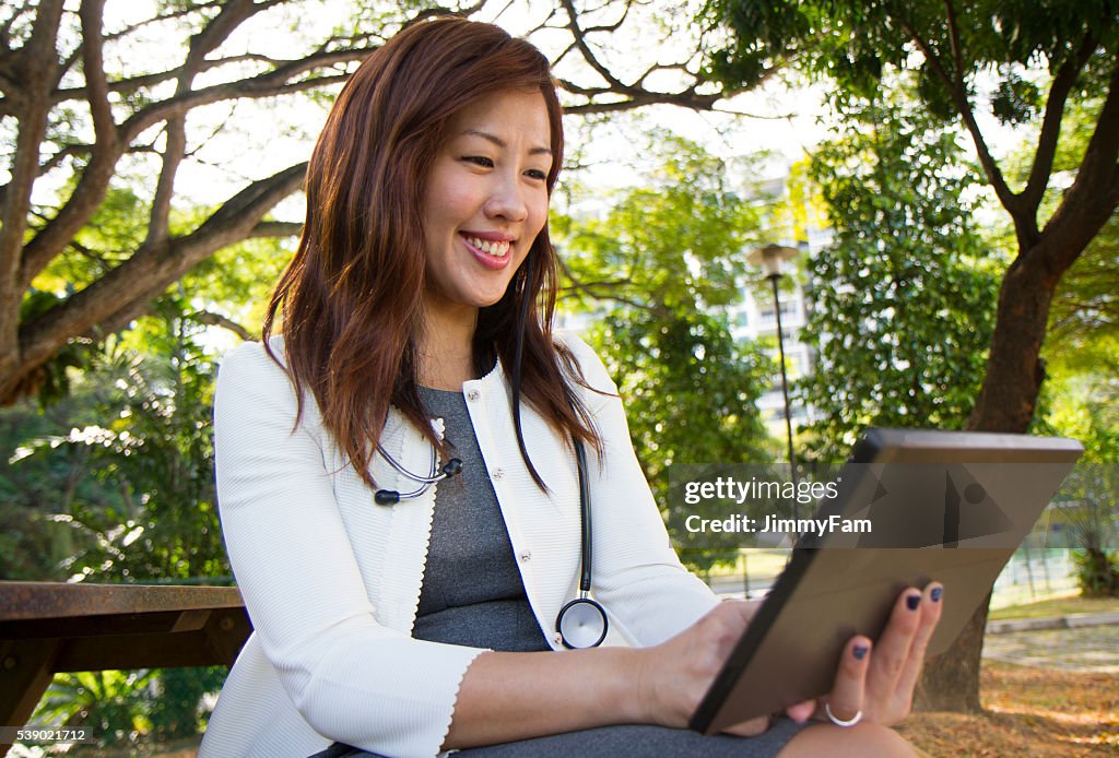 Asiatischen Arzt mit Digitaltablett im Freien