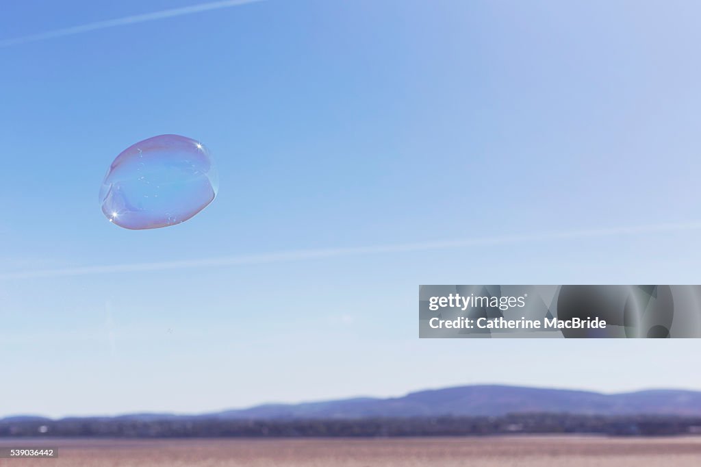 A single bubble floats through blue skies
