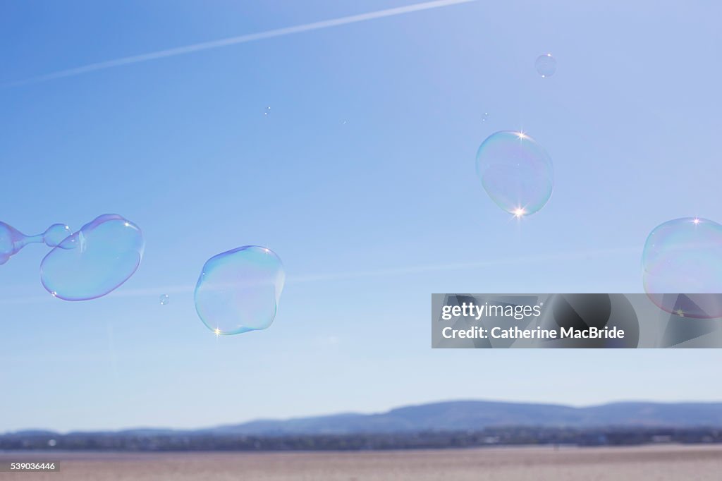 A group of bubbles float through blue skies