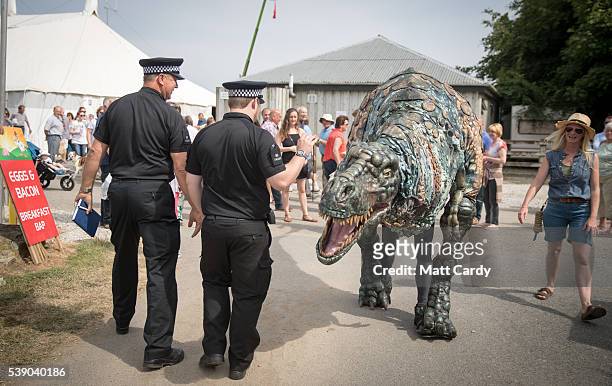 Police officers walk past the Eden Project's life-size juvenile Tyrannosaurus rex that has been brought as a preview to the nearby attraction's...
