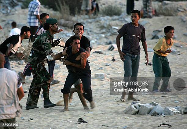 Palestinian security man tries to prevent youths from reaching an Israeli tank during clashes near the vacant Jewish settlement of Neve Dekalim on...