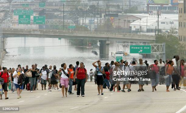 Survivors walk to high ground after being evacuated from high water to a highway September 1, 2005 in New Orleans, Louisiana. Rescue efforts continue...