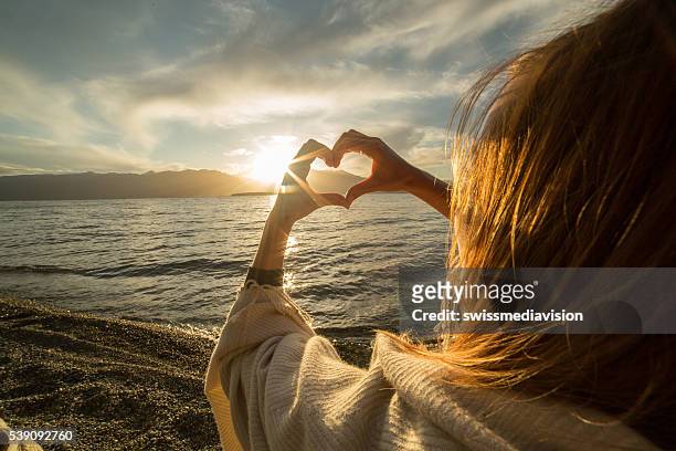 mujer joven con el corazón en forma de lago para hacer un marco con los dedos - an evening with heart fotografías e imágenes de stock