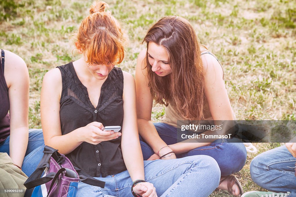 Two Young women playing with smartphone in a garden