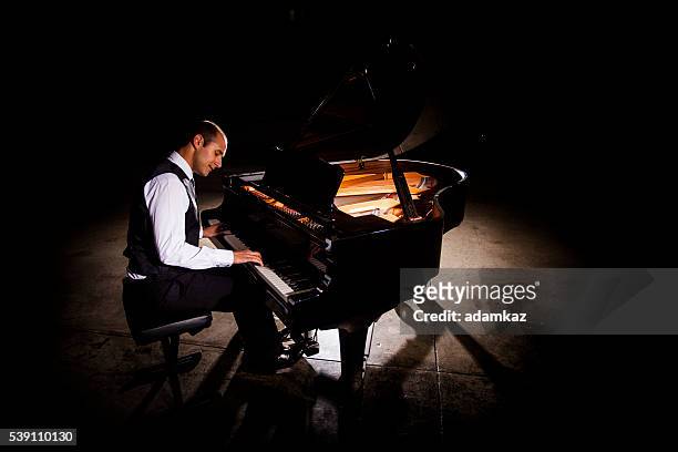 man playing piano with dramatic lighting - grand piano 個照片及圖片檔