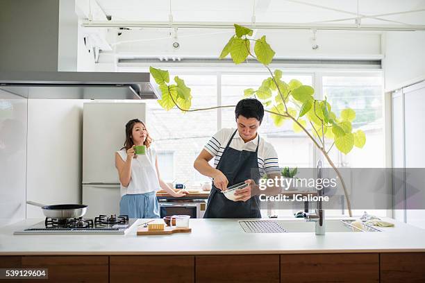 young adult couple in the kitchen together - simple living room stock pictures, royalty-free photos & images