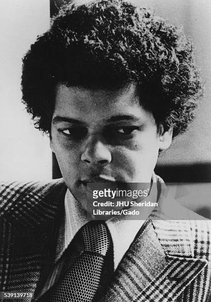 Head shot of politician Julian Bond, wearing a patterned suit and tie with a light patterned shirt, with a serious facial expression, 1975. .
