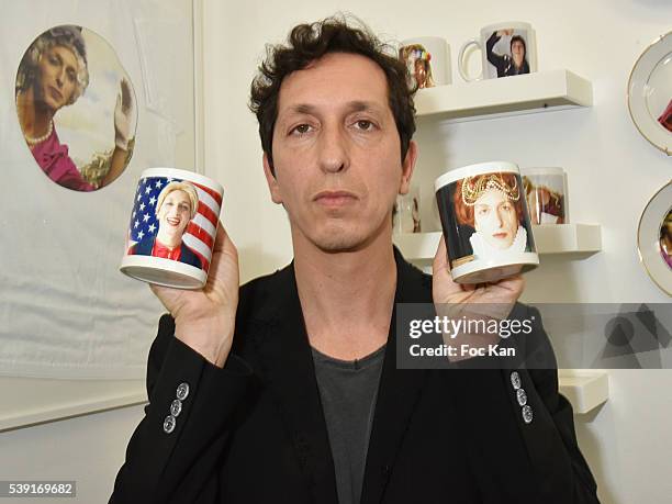 Stephane Foenkinos poses with two mugs decorated of himself travestite in Queen Victoria and Hillary Clinton during "55 Politiques" : Exhibition...