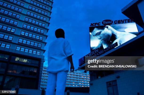 Man watches a slide show of Muhammad Ali photos displayed on a screen outside the KFC Yum! Center where mourners will attend a memorial service for...