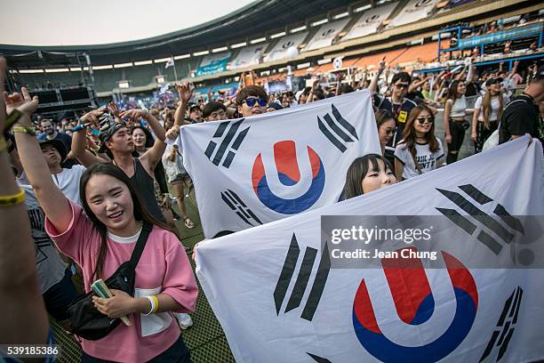 South Korean youths holding Korean flags altered with the Ultra Music Festival's logo dance to electronic music during the Ultra Music Festival Korea...