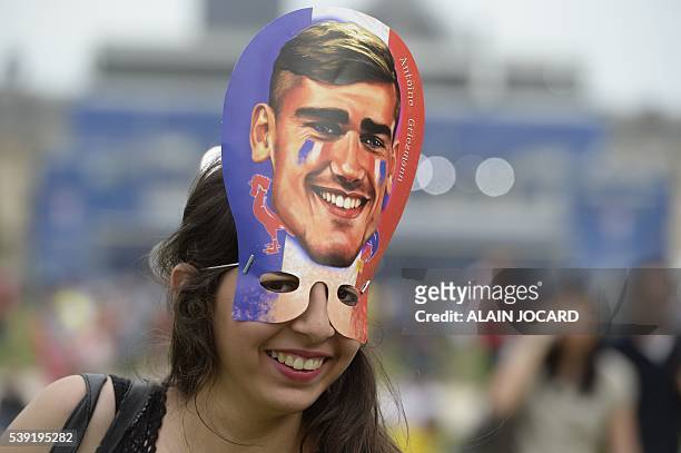 French supporter wearing a mask representing French football team forward Antoine Griezmann smiles inside a fanzone ahead of the first football...