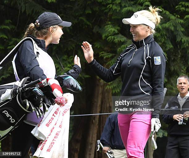 Brooke Henderson of Canada celebrates with her caddie after making a hole-in-one on the 13th hole in the opening round of the Women's PGA...