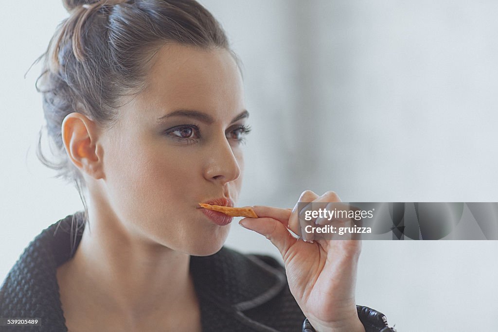 Beautiful young woman eating muesli bar snack