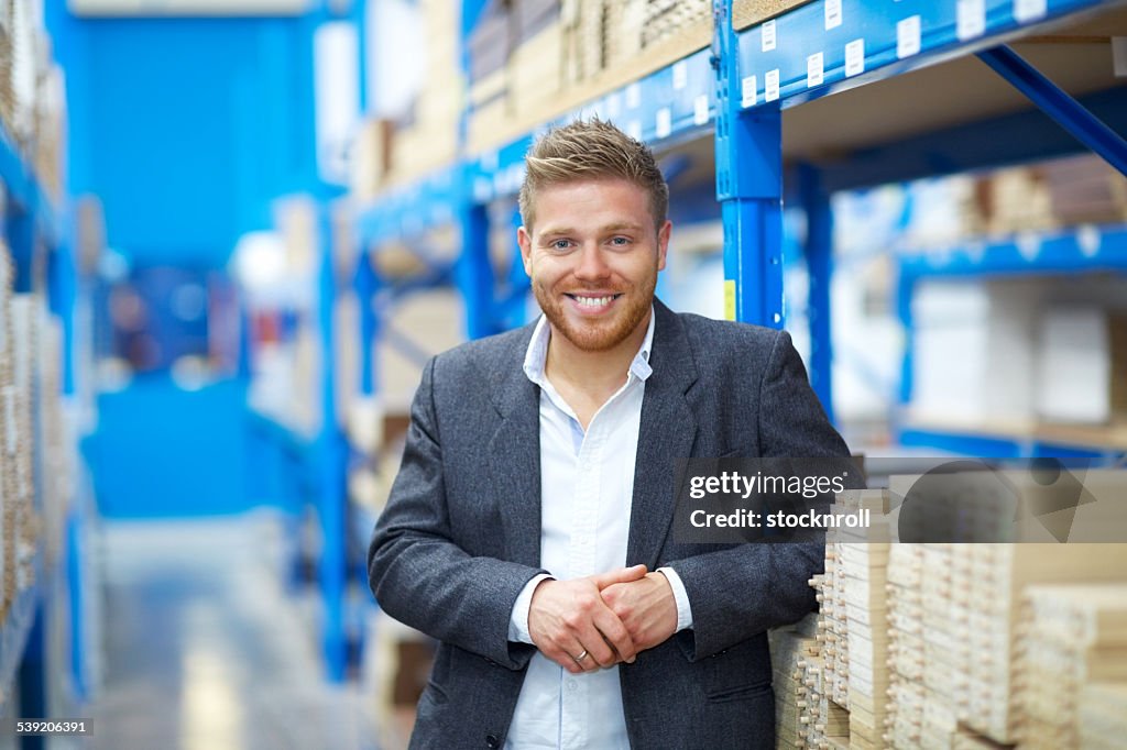 Confident young businessman standing in warehouse