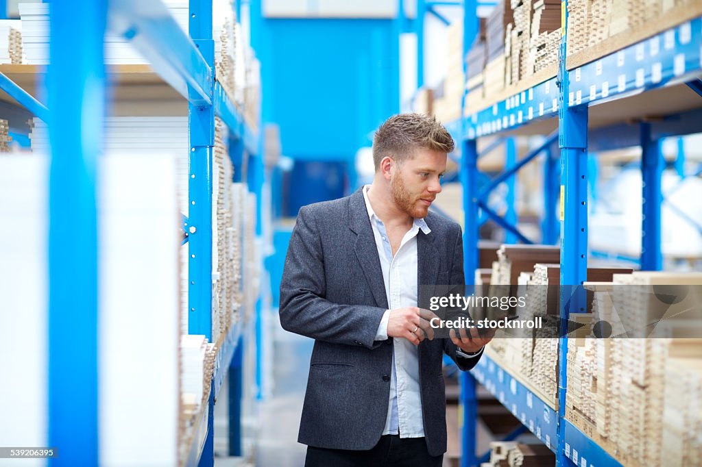 Young businessman in warehouse checking inventory