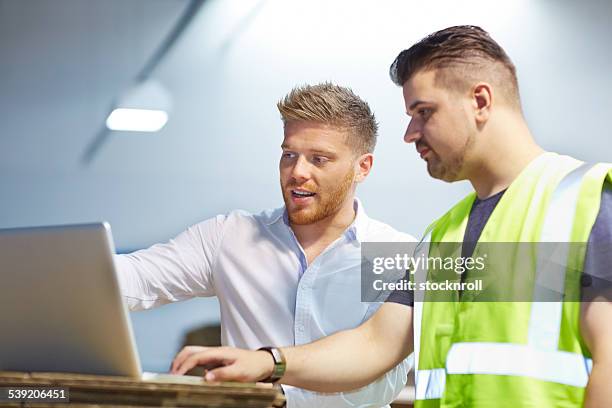 gerente de jóvenes trabajando con capataz en fábrica - material reflector de seguridad fotografías e imágenes de stock