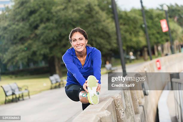 middle aged woman stretching after a jog in the park - power walking stock pictures, royalty-free photos & images