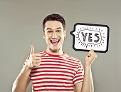 Young man holding speech bubble with text yes