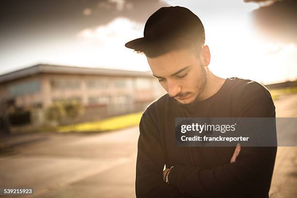 fashionable young adult looking away at dusk - man sadness stock pictures, royalty-free photos & images