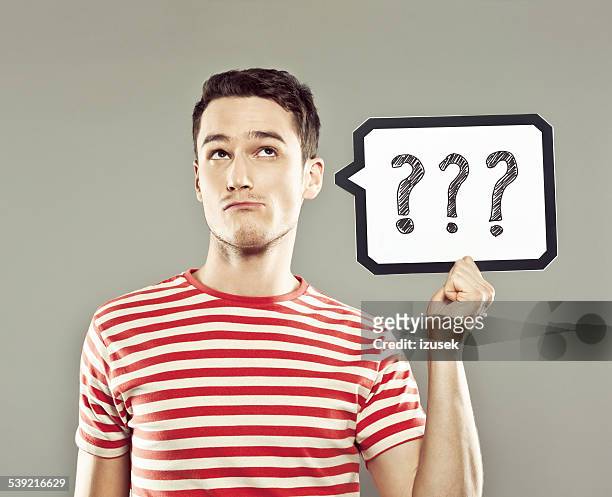 young man holding speech bubble with question marks - manquestionmark stock pictures, royalty-free photos & images
