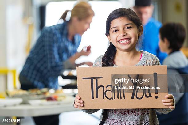 happy little girl holding thank you sign in food bank - grateful words stock pictures, royalty-free photos & images