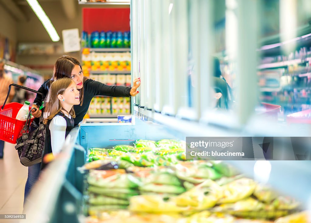 Mother and daughter in supermarket near frozen food