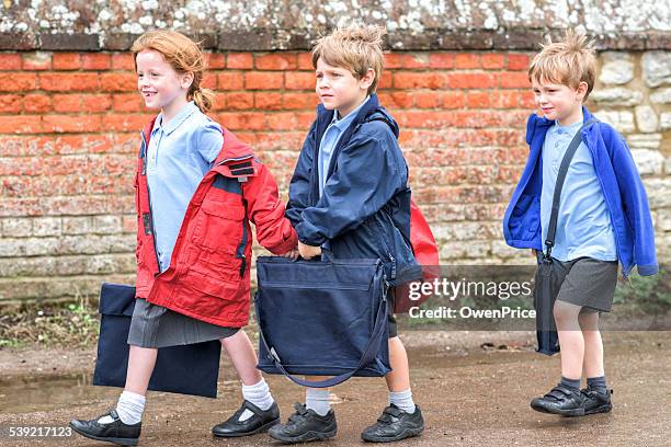 children walking to uk primary school - satchel stock pictures, royalty-free photos & images