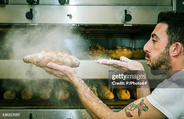 young man (baker) blows the flour on bread - bread oven stock pictures, royalty-free photos & images
