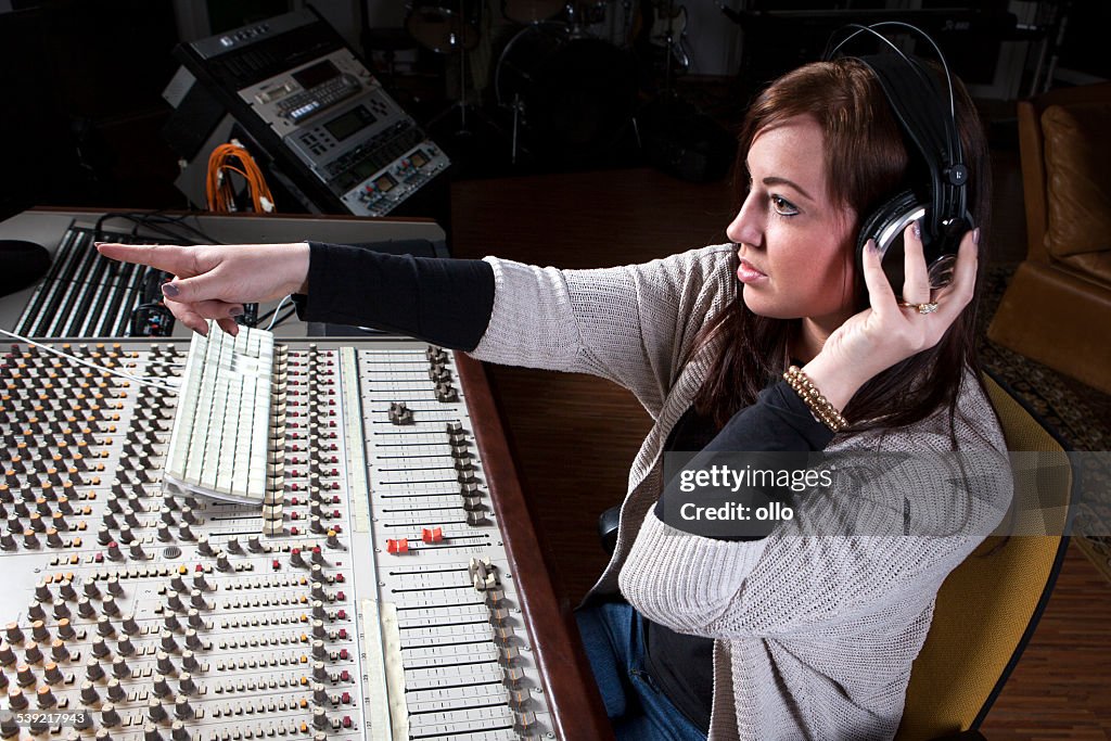 Female sound engineer at studio mixing desk