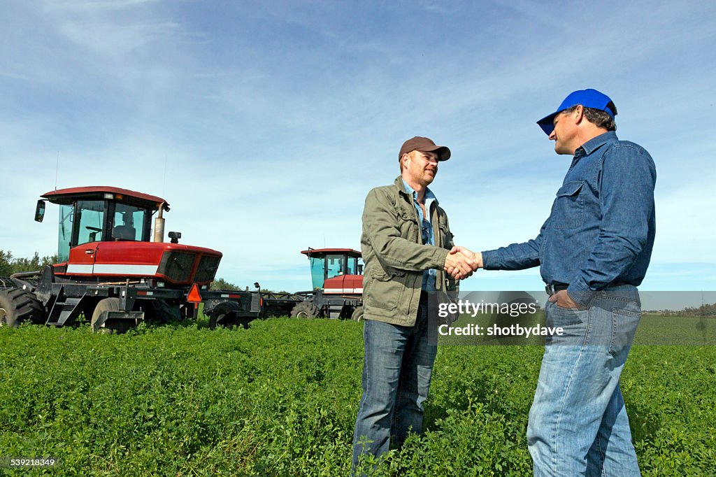 Bauern Hände schütteln auf einer Farm mit Tractors