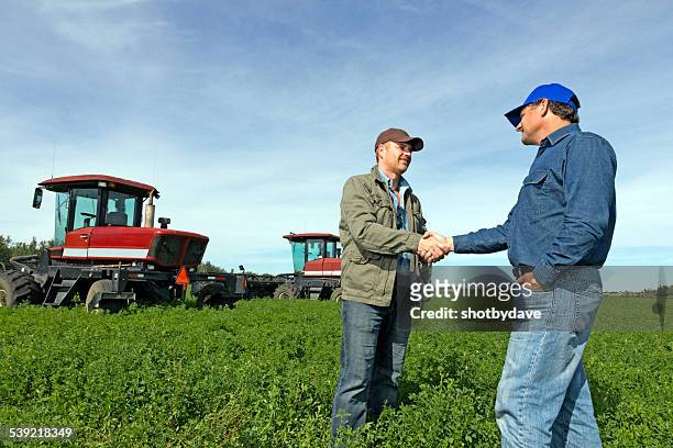 les agriculteurs poignée de main dans une ferme avec tractors - champs tracteur photos et images de collection