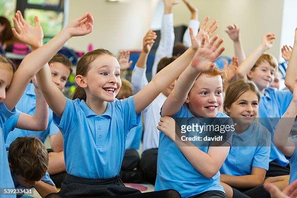 excited school children in uniform with hands up - school uniform stock pictures, royalty-free photos & images