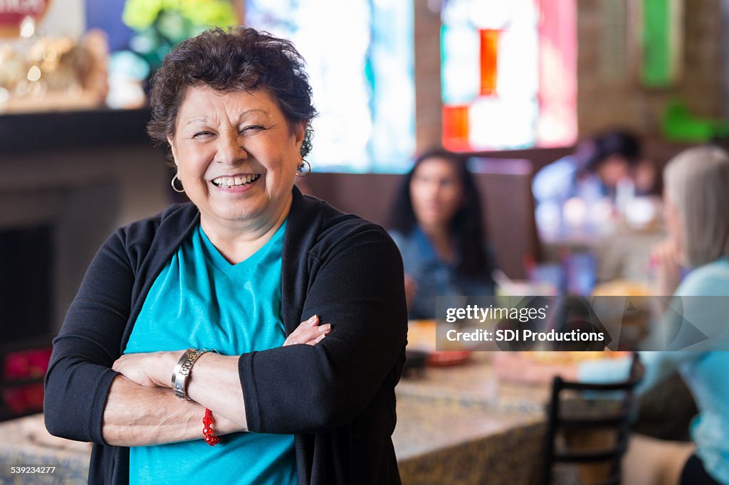 Hispanic grandmother smiling in dining room of family owned restaurant