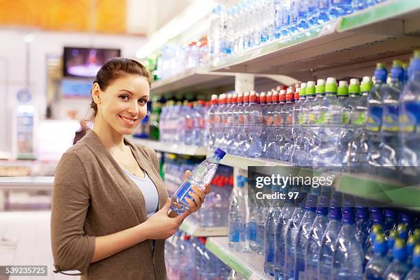 woman buys a water bottle in shop - holding soda bottle stock pictures, royalty-free photos & images