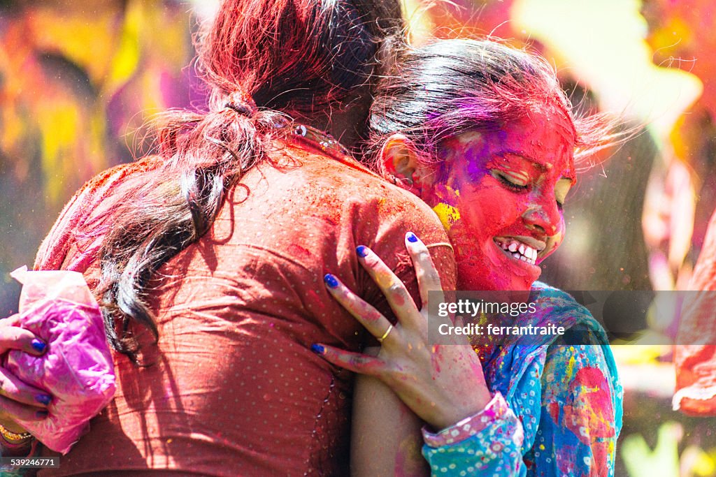 Indian women covered with holi powder hugging each other