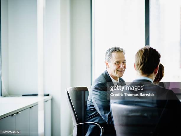 smiling mature businessman leading team discussion - wisdom knowledge modern stockfoto's en -beelden