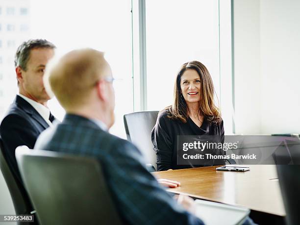 business executive leading meeting with colleagues - meeting candid office suit stock pictures, royalty-free photos & images