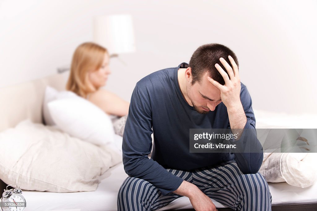 Mann sitzt auf dem Bett mit der Frau auf der Rückseite