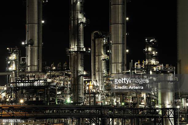 Refinery chimneys of petrochemical industry illuminated at night.