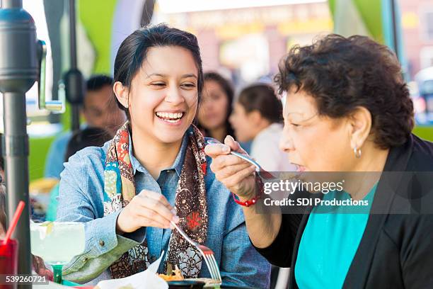 happy hispanic woman having lunch with grandmother at restaurant - mexican restaurant stock pictures, royalty-free photos & images