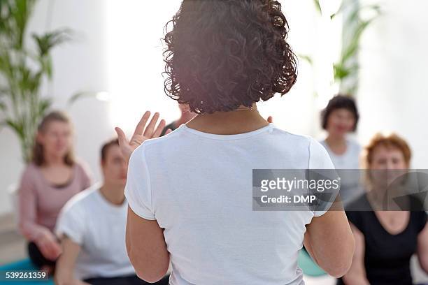 female instructor guiding student during yoga class - coach stock pictures, royalty-free photos & images