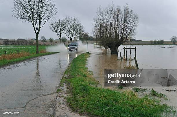 Flooded brook, road and field at Huise in Flanders, Belgium.