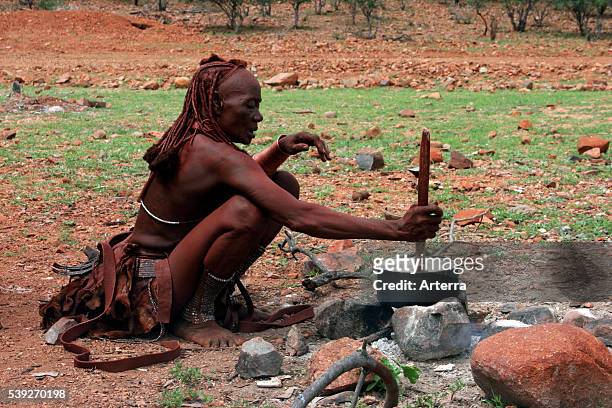 Himba woman cooking in pot on open fire Kaokoland / Kaokoveld, Kunene Region, Northern Namibia, South Africa.